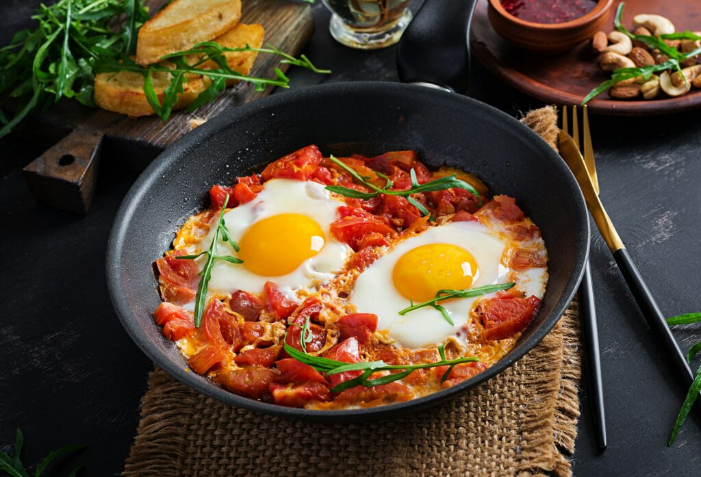 Late breakfast - fried eggs with vegetables. Shakshuka. Arabic cuisine. Kosher food.
