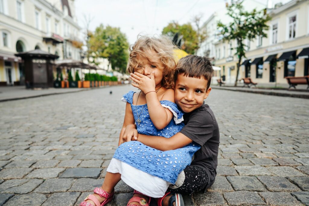 little boy and girl are sitting on the street