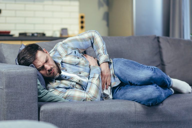 hombre con dolor abdominal acostado en un sofa
